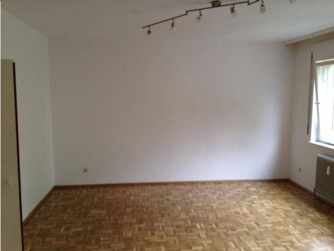 Geräumiger, leerer Raum mit Parkettboden und einem Fenster, bereit zur individuellen Gestaltung.