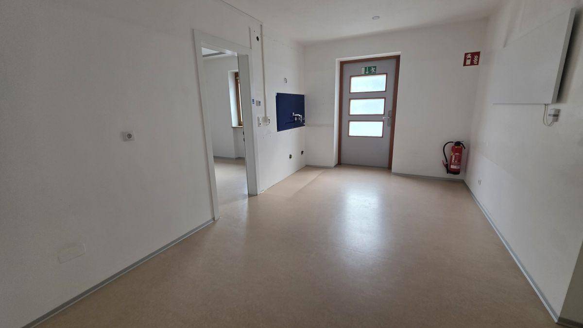 Geräumiger Flur mit hellem Boden, weiß gestrichenen Wänden und einer Eingangstür.