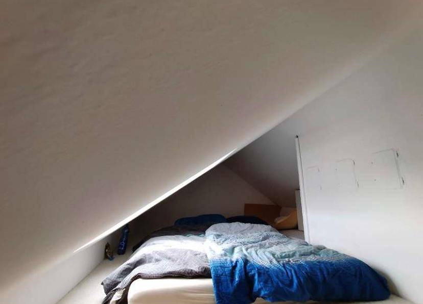 Gemütliches Schlafzimmer mit Bett unter einer ausgeprägten Dachschräge, ideal für Dachgeschosswohnungen.