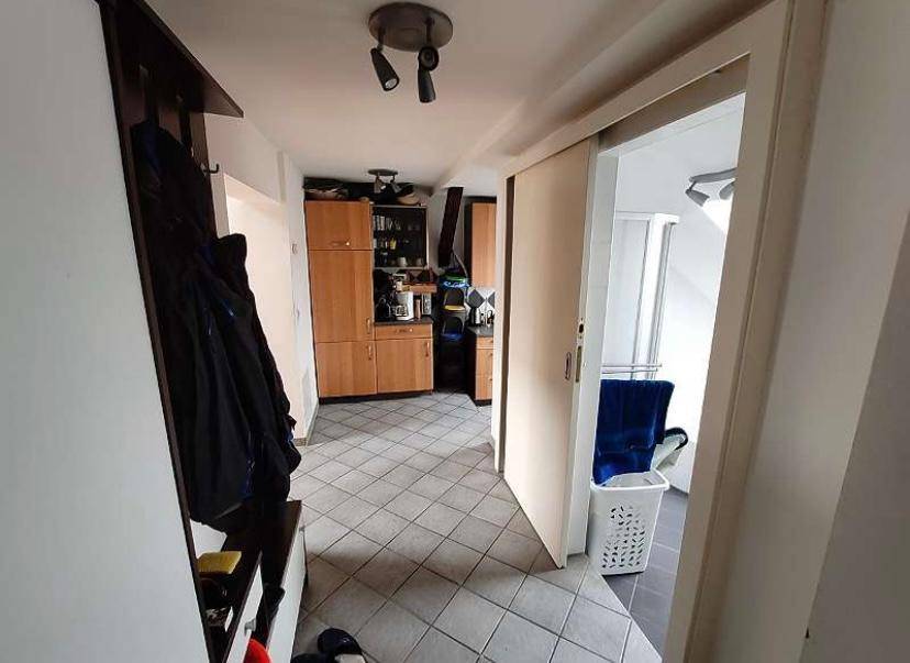 Flur mit Fliesenboden, Garderobe und Zugang zur Küche sowie einem weiteren Raum.