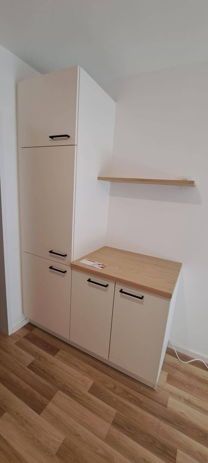 Hoher Küchenschrank und Unterschränke mit Holzplatte und offener Ablage.