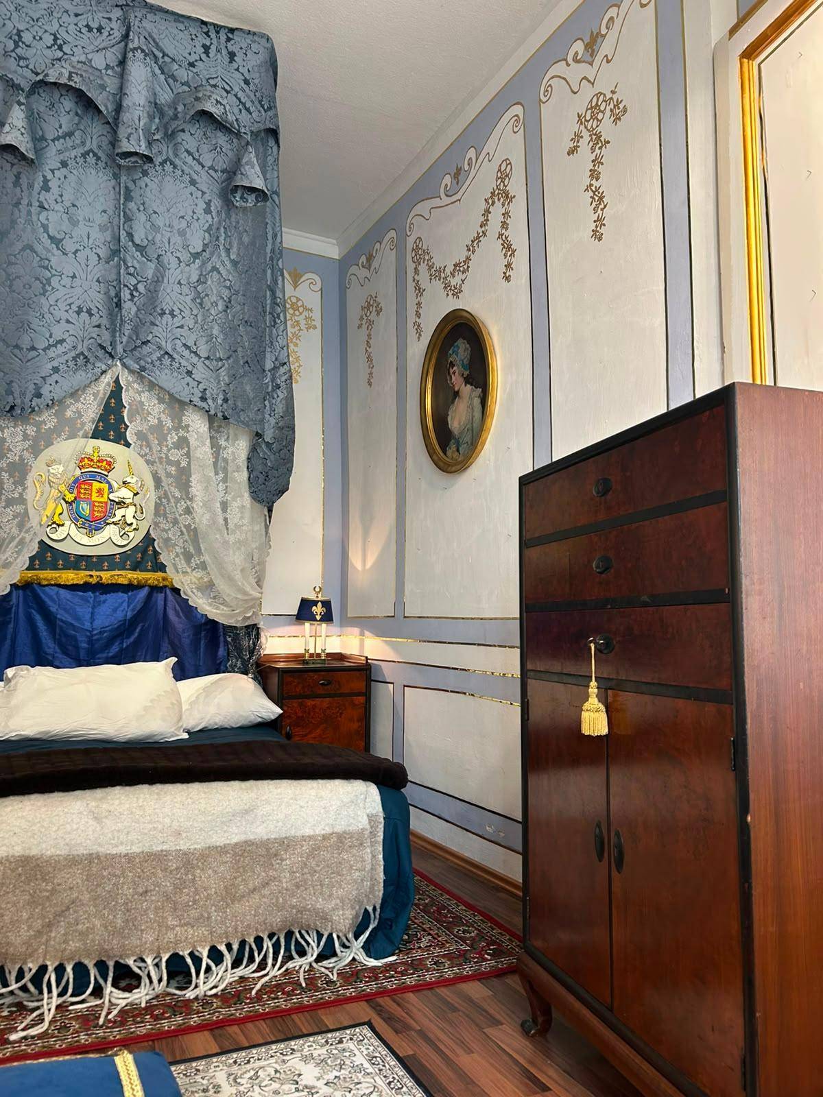 Detailansicht eines Schlafzimmers mit antikem Holzschrank und kunstvollen Wandmalereien.