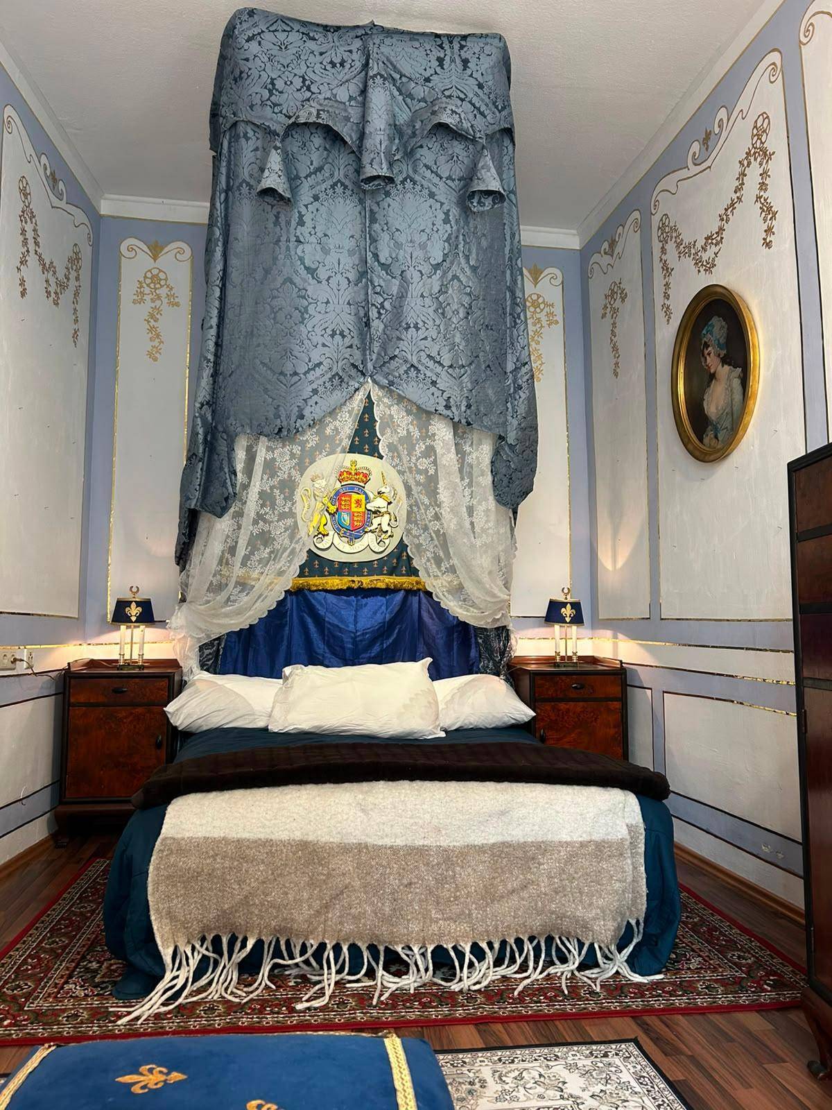 Königliches Schlafzimmer mit Himmelbett, antiken Nachttischen und aufwendiger Wandverzierung.