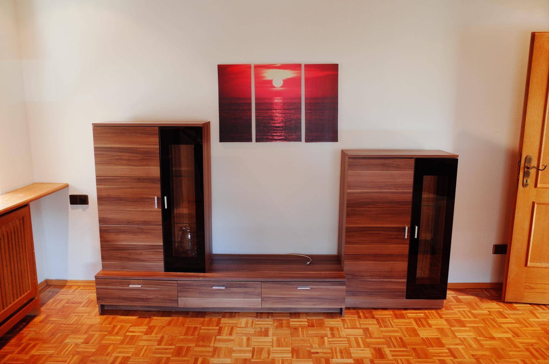 Wohnzimmerwand mit modernem Holzmöbel und dekorativem Kunstwerk über dem Sideboard.