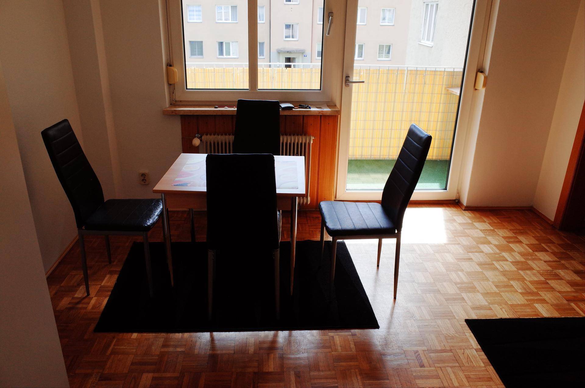 Essbereich mit kleinem Tisch und Stühlen, direkt neben einem Fenster und Zugang zum Außenbereich.