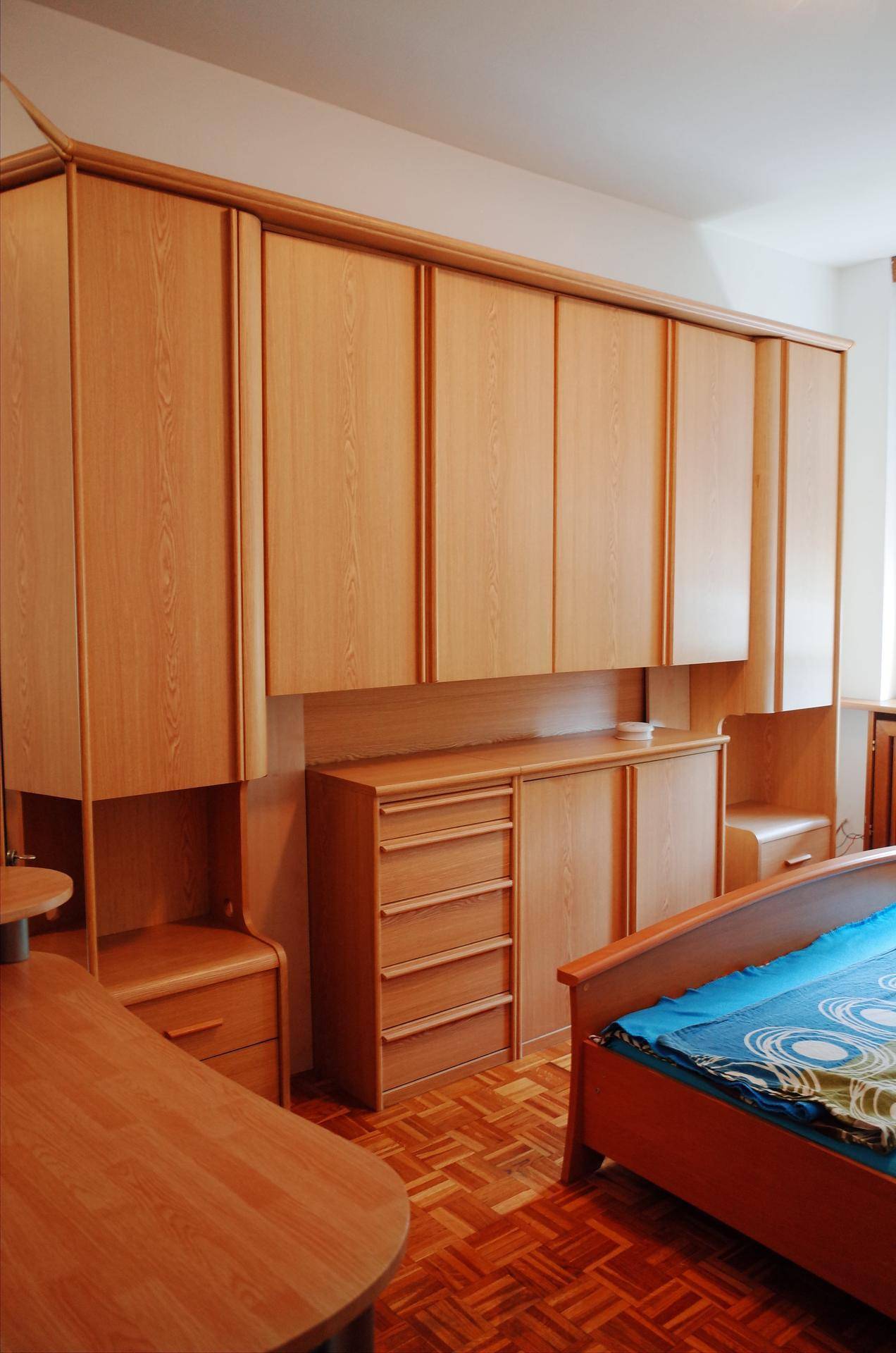 Schlafzimmer mit umfangreichen Einbauschränken aus Holz und einem bequemen Bett.