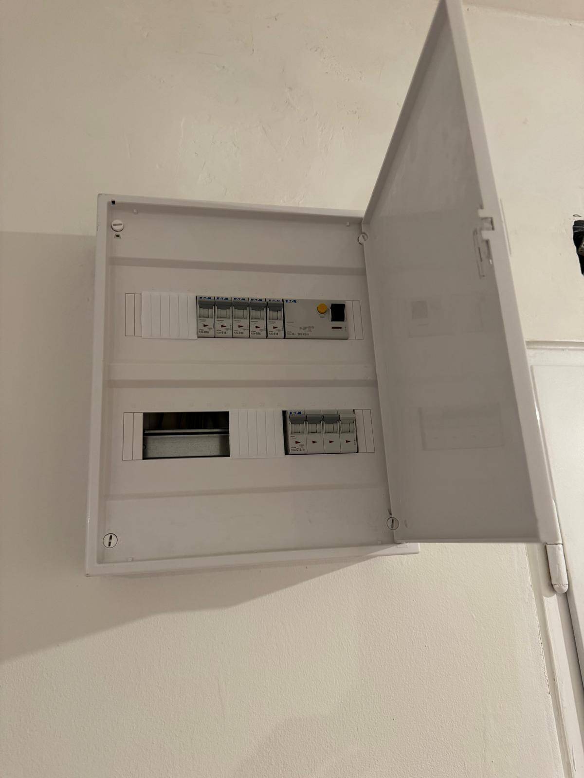 Offener Sicherungskasten an einer weißen Wand, der die moderne Elektroinstallation zeigt.