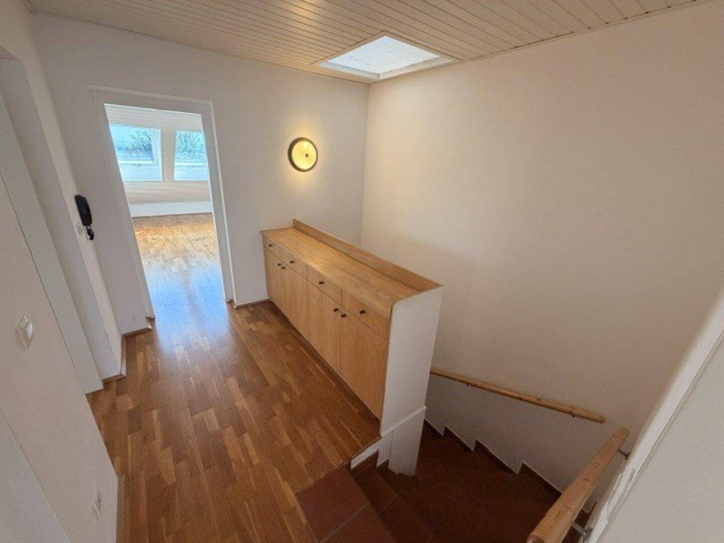 Flur mit Holzfußboden, eingebautem Holzschrank und Treppe, die in den unteren Bereich führt.