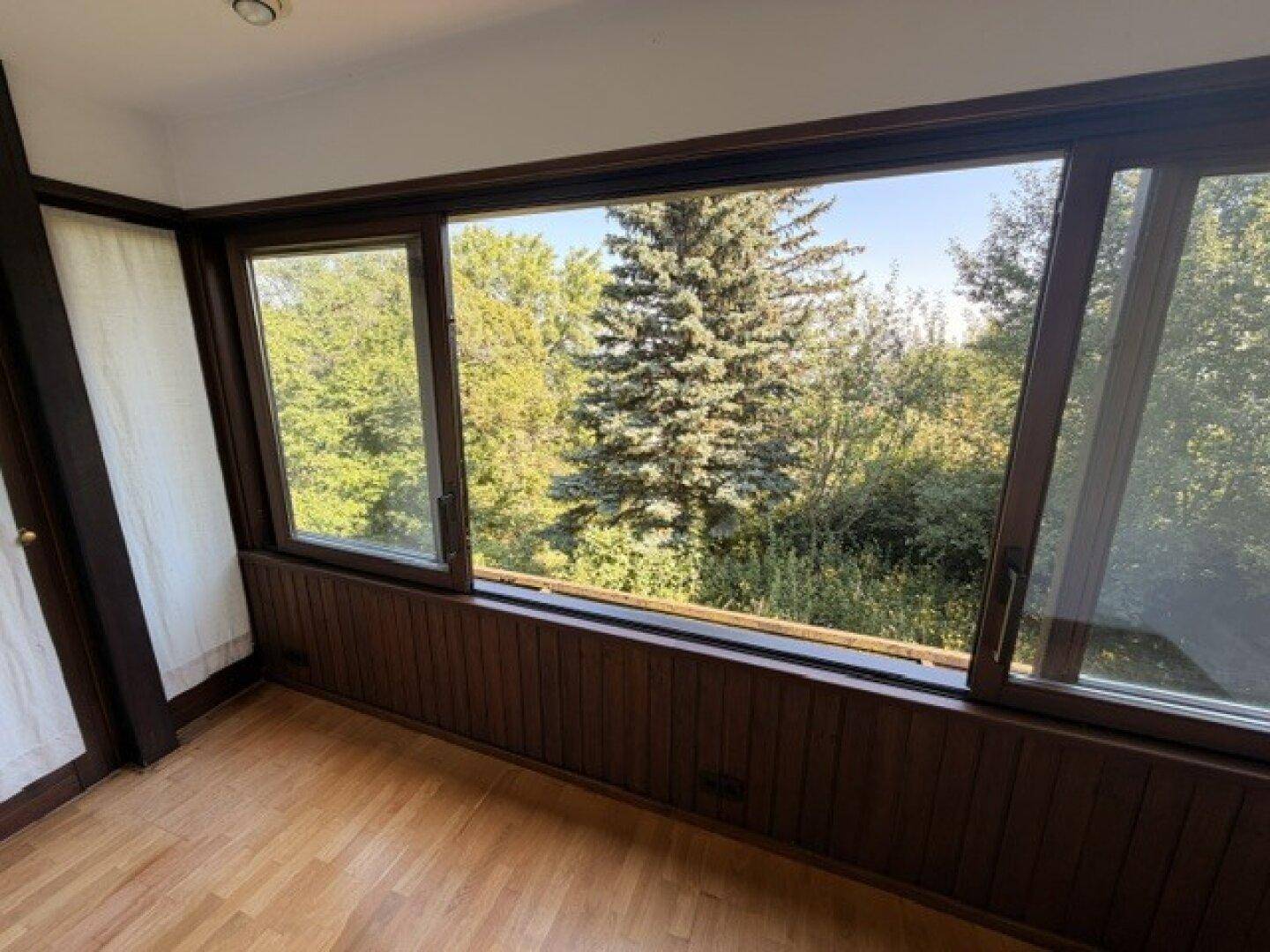 Helle Loggia mit weitem Blick auf die umliegenden Bäume und die Natur.