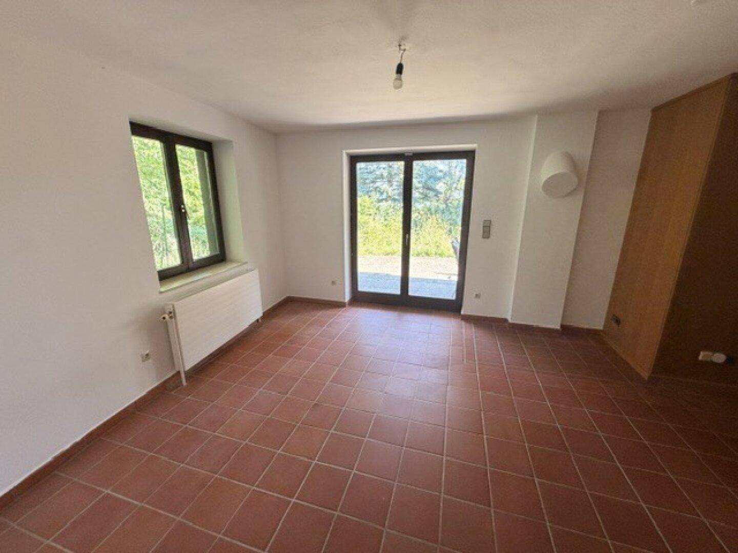 Geräumiges Zimmer mit Terrakottafliesen und direktem Zugang zu einer Außenterrasse.