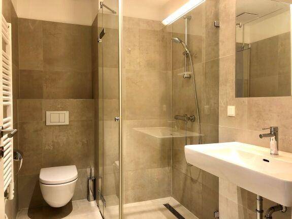 Modernes Badezimmer mit begehbarer Dusche, Wand-WC und beheiztem Handtuchhalter für Komfort und Stil.