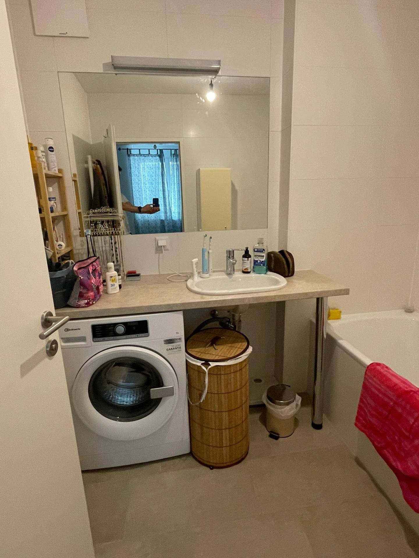Modernes Badezimmer mit Waschmaschine, Einzelwaschbecken, großem Spiegel und Badewanne.