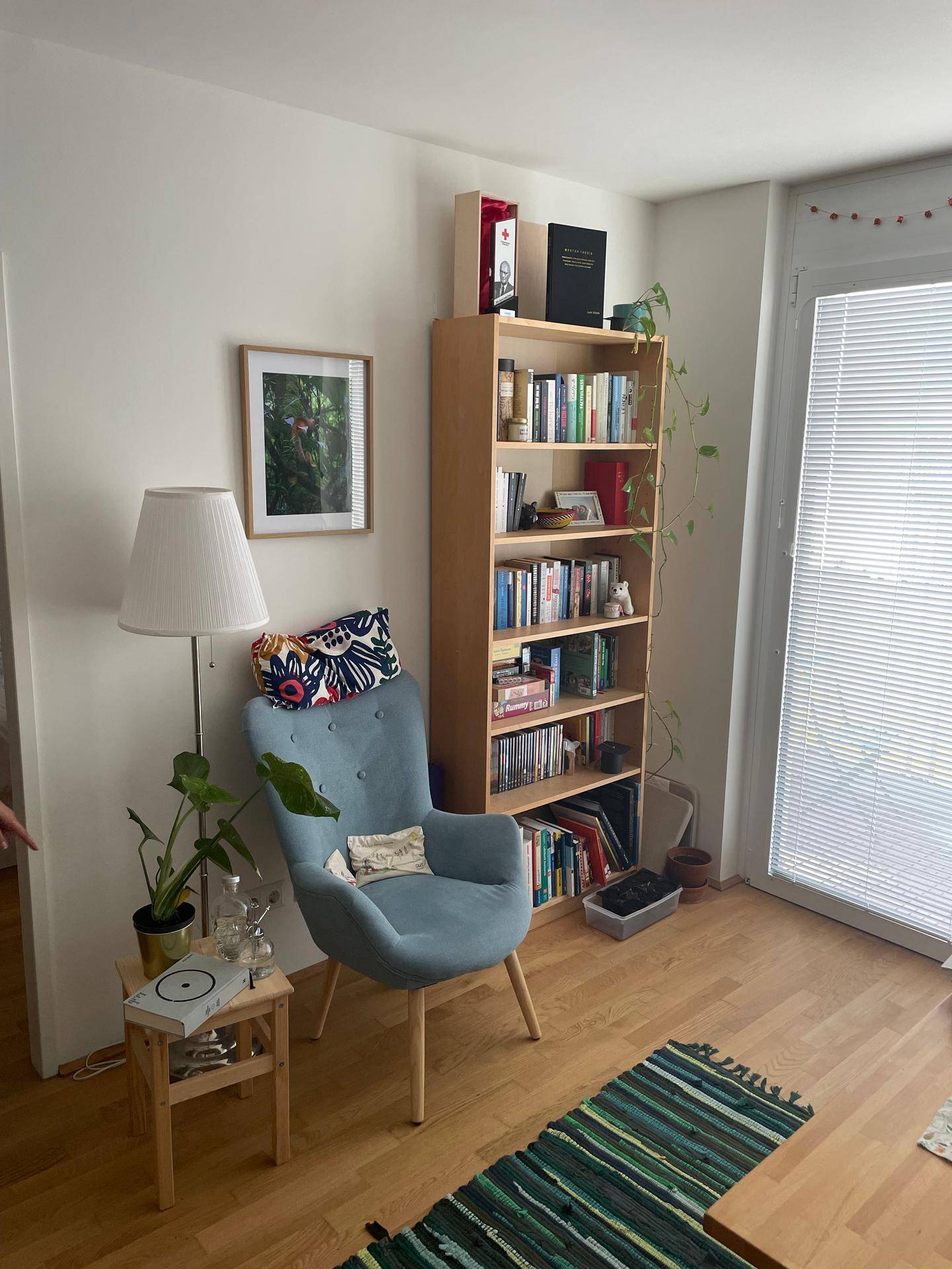 Gemütliche Leseecke im Wohnzimmer mit Sessel, Stehlampe, Bücherregal und Holzboden.