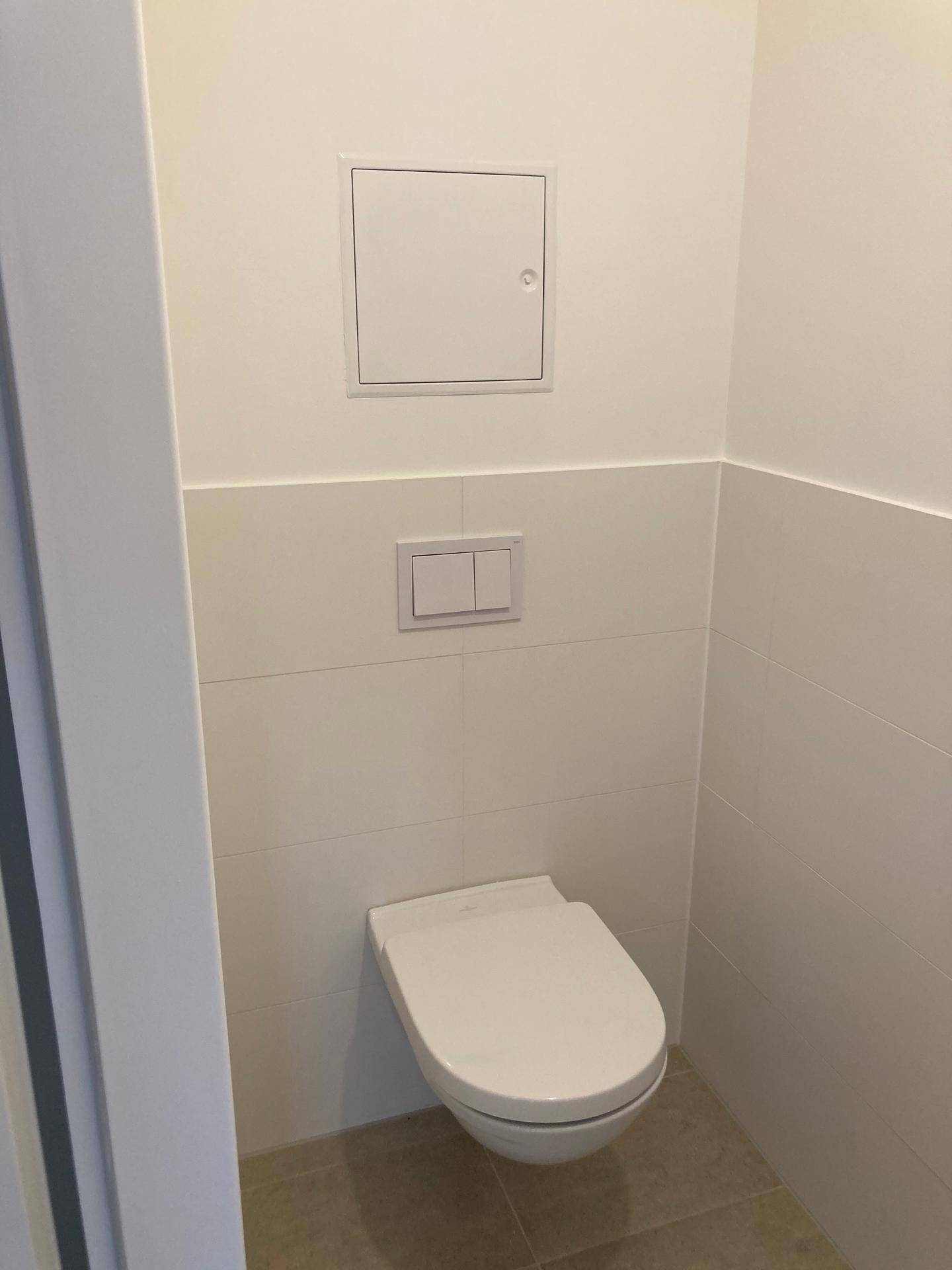 Modernes Gäste-WC mit wandhängendem WC und halbhoch gefliesten Wänden und Boden.