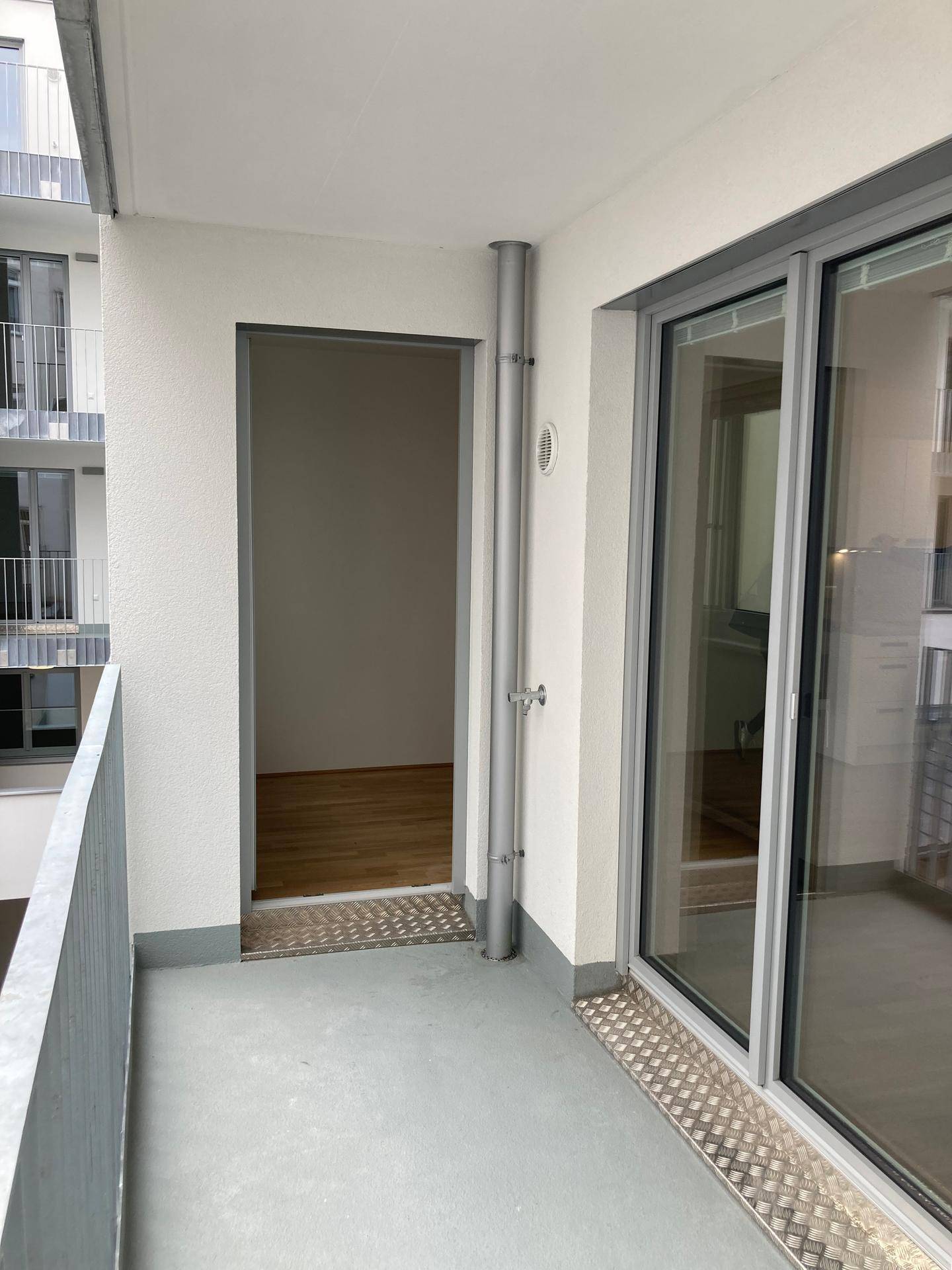 Balkon mit Blick auf den Innenhof und Zugang zu einem hellen Innenraum der Wohnung.