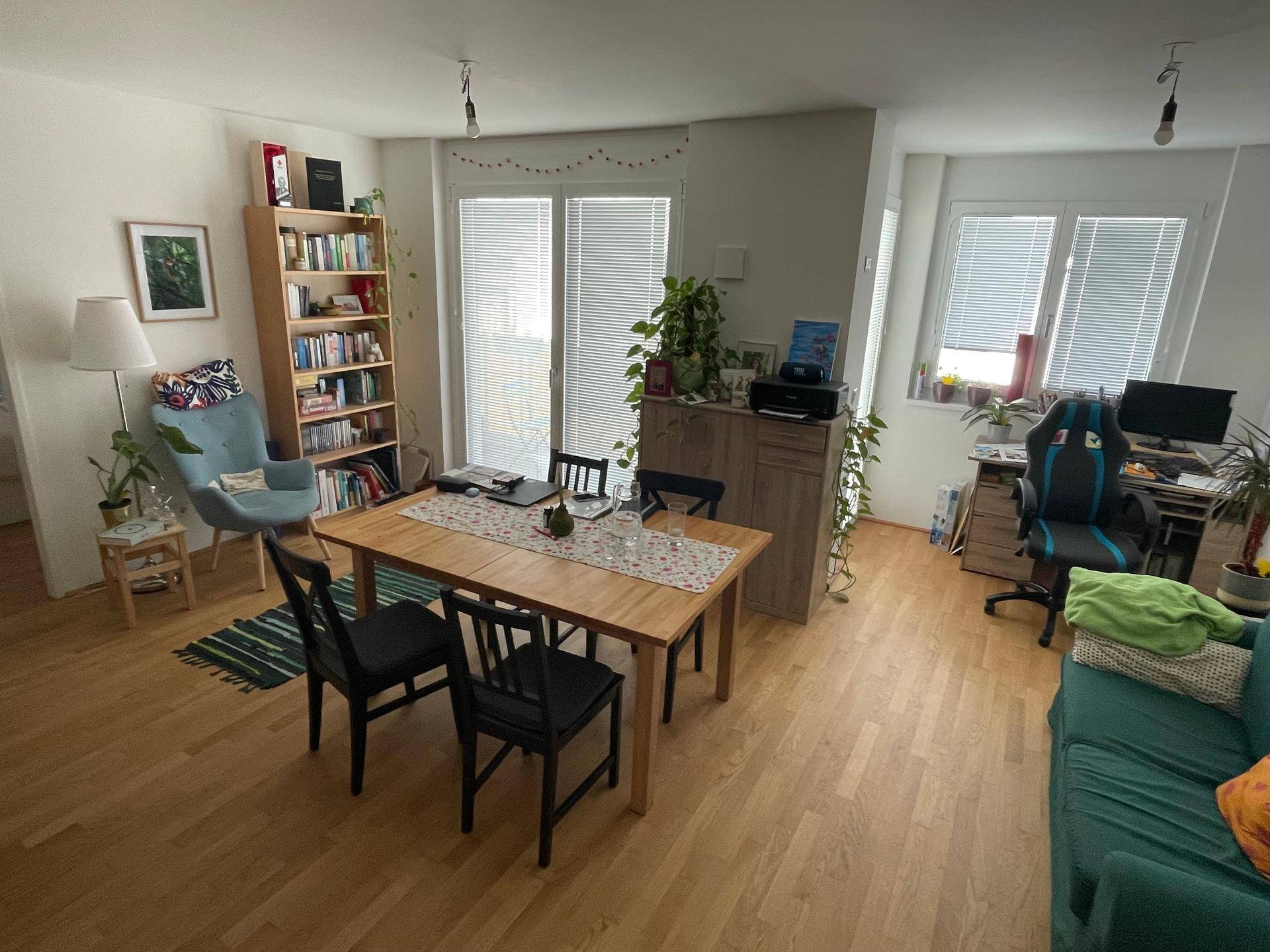 Geräumiger Wohn- und Essbereich mit Parkettboden, Bücherregal und viel Tageslicht.