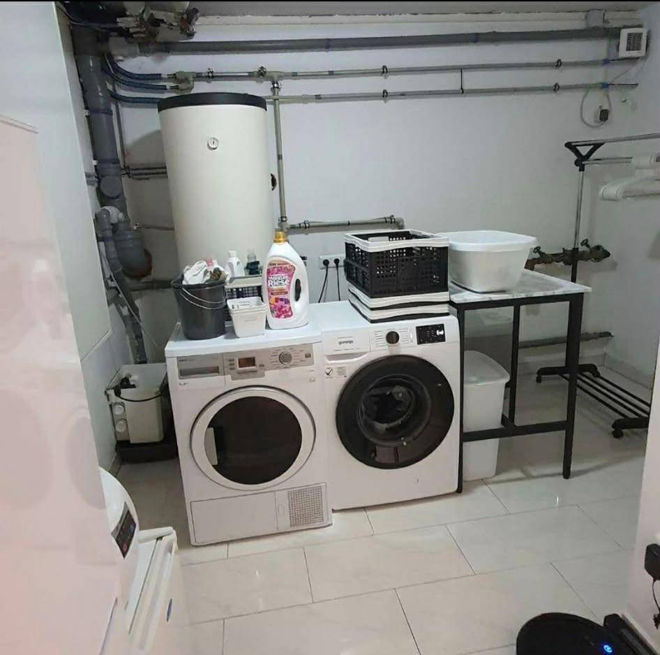 Funktionaler Waschraum im Keller mit Waschmaschine, Trockner und Warmwasserboiler für den Haushalt.