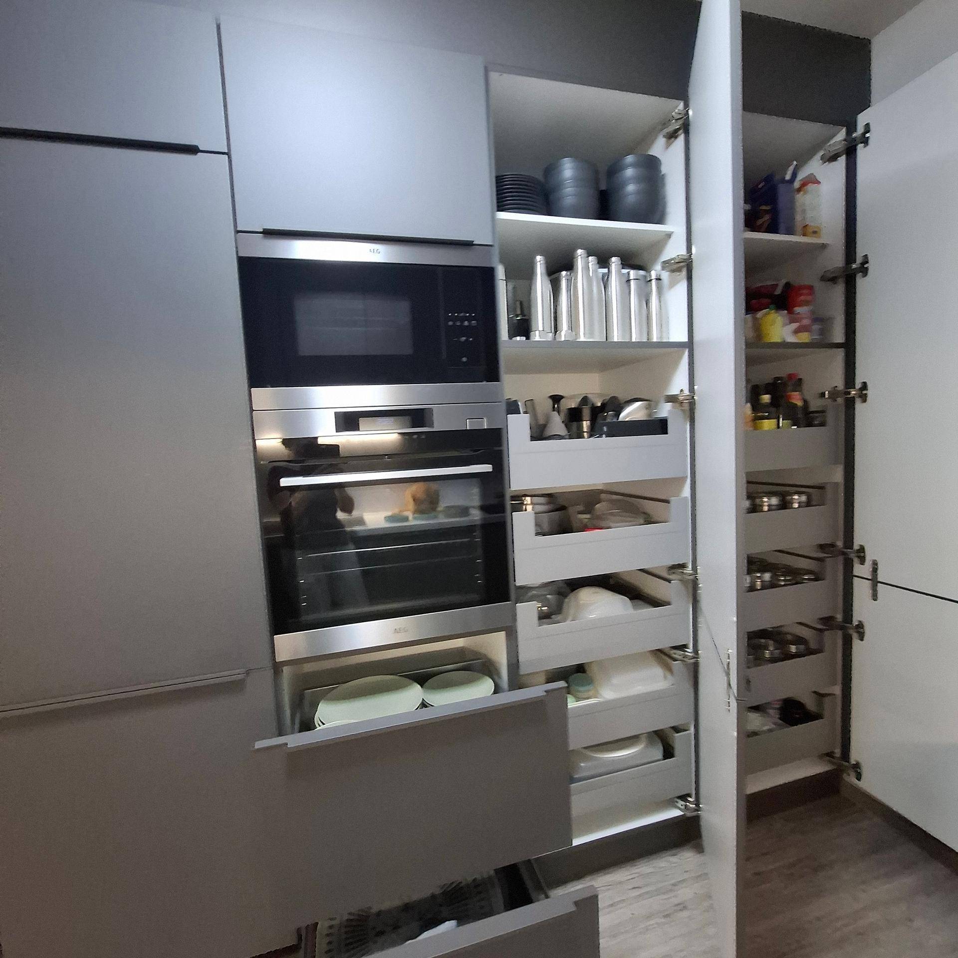 Integrierte Küchengeräte mit Backofen, Mikrowelle und praktischen Auszügen für Geschirr und Vorräte.