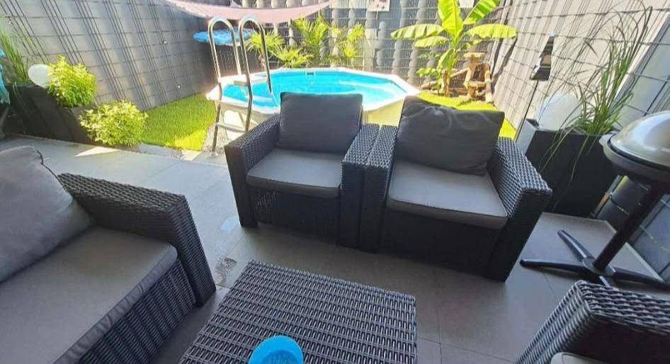 Gemütlicher Außenbereich mit Rattanmöbeln und einem kleinen Aufstellpool im privaten Garten.