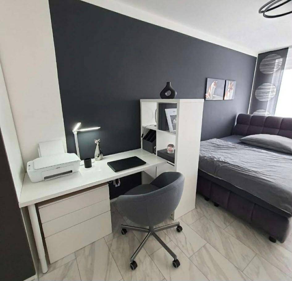 Schlafzimmer mit integriertem Arbeitsbereich, Schreibtisch und bequemem Bett.