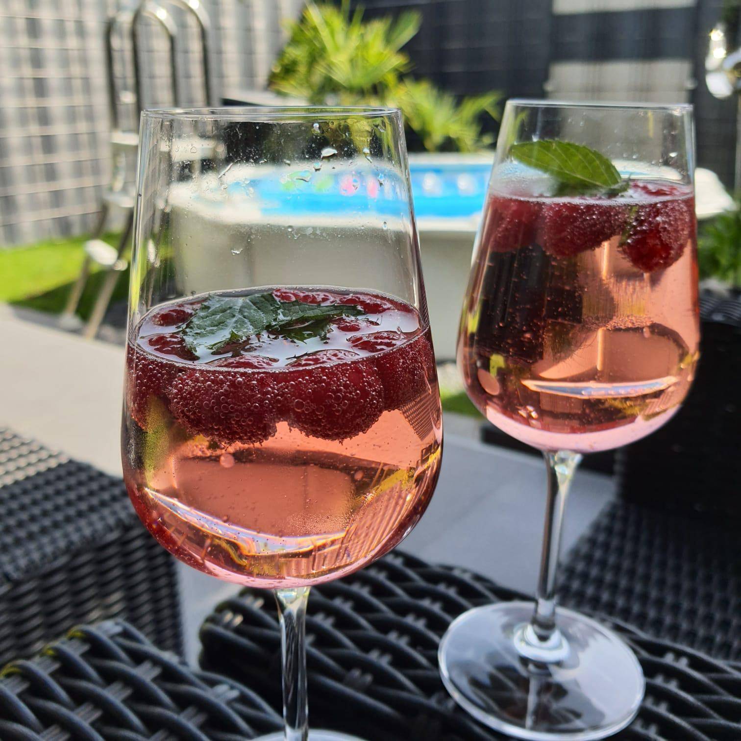 Erfrischende Getränke mit Himbeeren am Pool, perfekt für sonnige Tage im Gartenbereich.