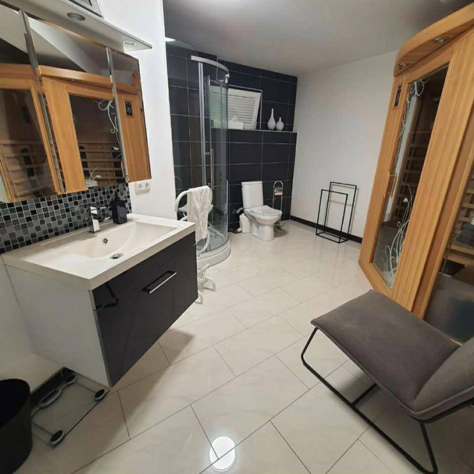 Geräumiges Badezimmer mit Waschbecken, Dusche, WC und integrierter Sauna.