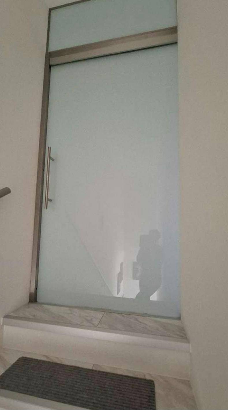 Moderne Milchglastür am oberen Ende eines Treppenhauses, die zu einem weiteren Bereich führt.