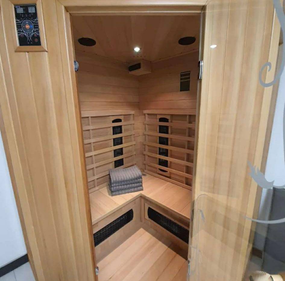 Innenansicht einer modernen Holzsauna mit bequemen Bänken und Infrarotstrahlern.