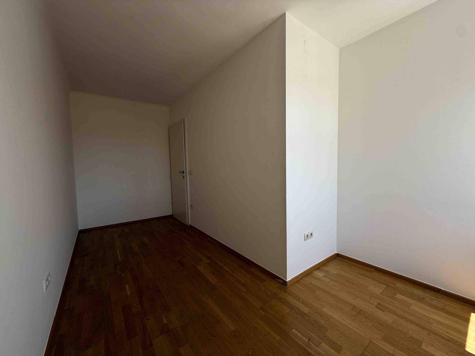 Geräumiger, leerer Raum mit Parkettboden und weißen Wänden, ideal für Schlaf- oder Kinderzimmer.