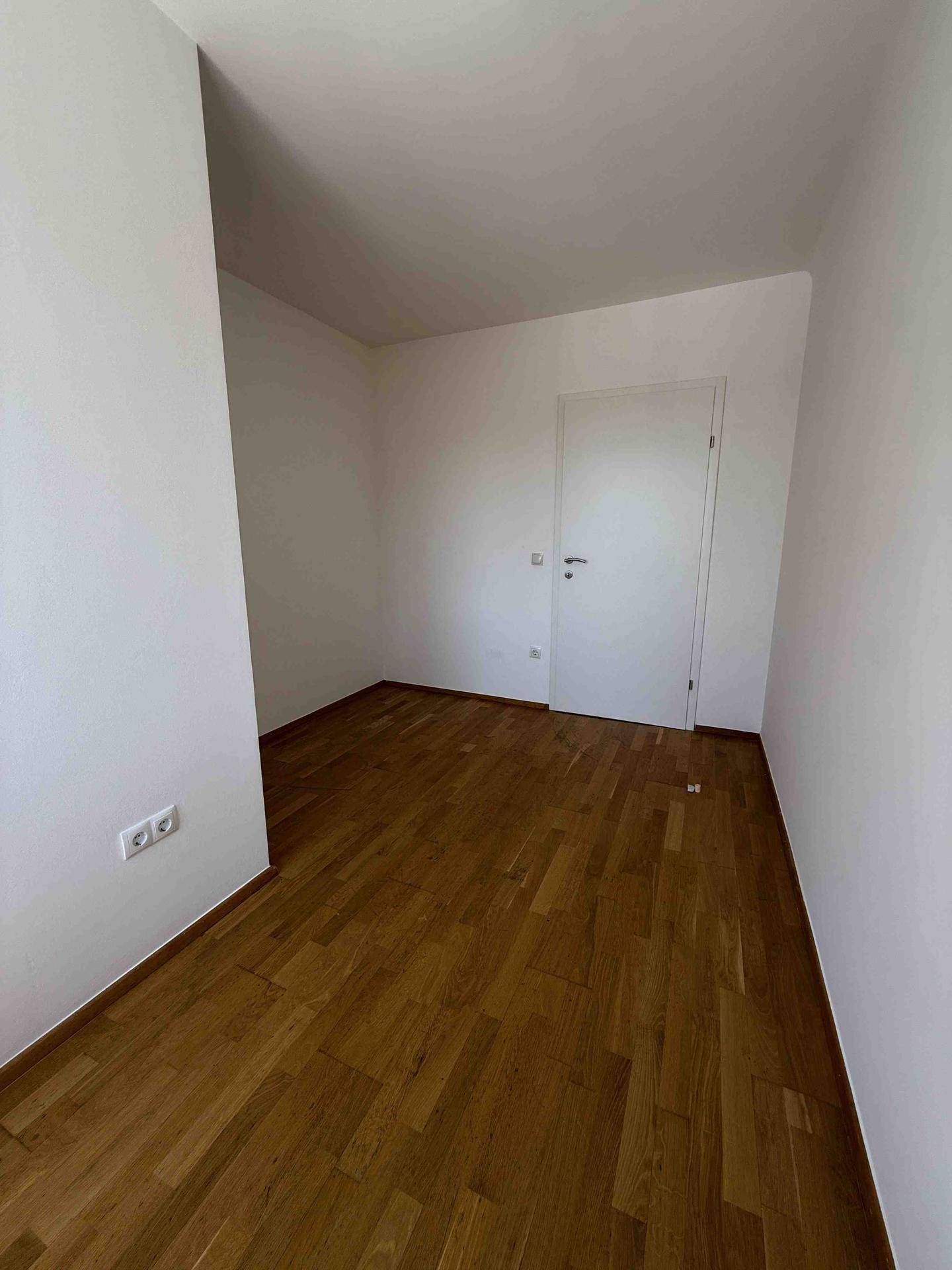 Kleinerer Raum mit hellem Parkettboden und weißen Wänden, ideal als Schlaf- oder Arbeitszimmer.
