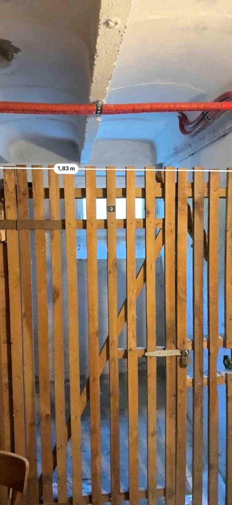 Praktischer Abstellraum oder Kellerabteil mit Holzlattenwänden und niedriger Deckenhöhe.