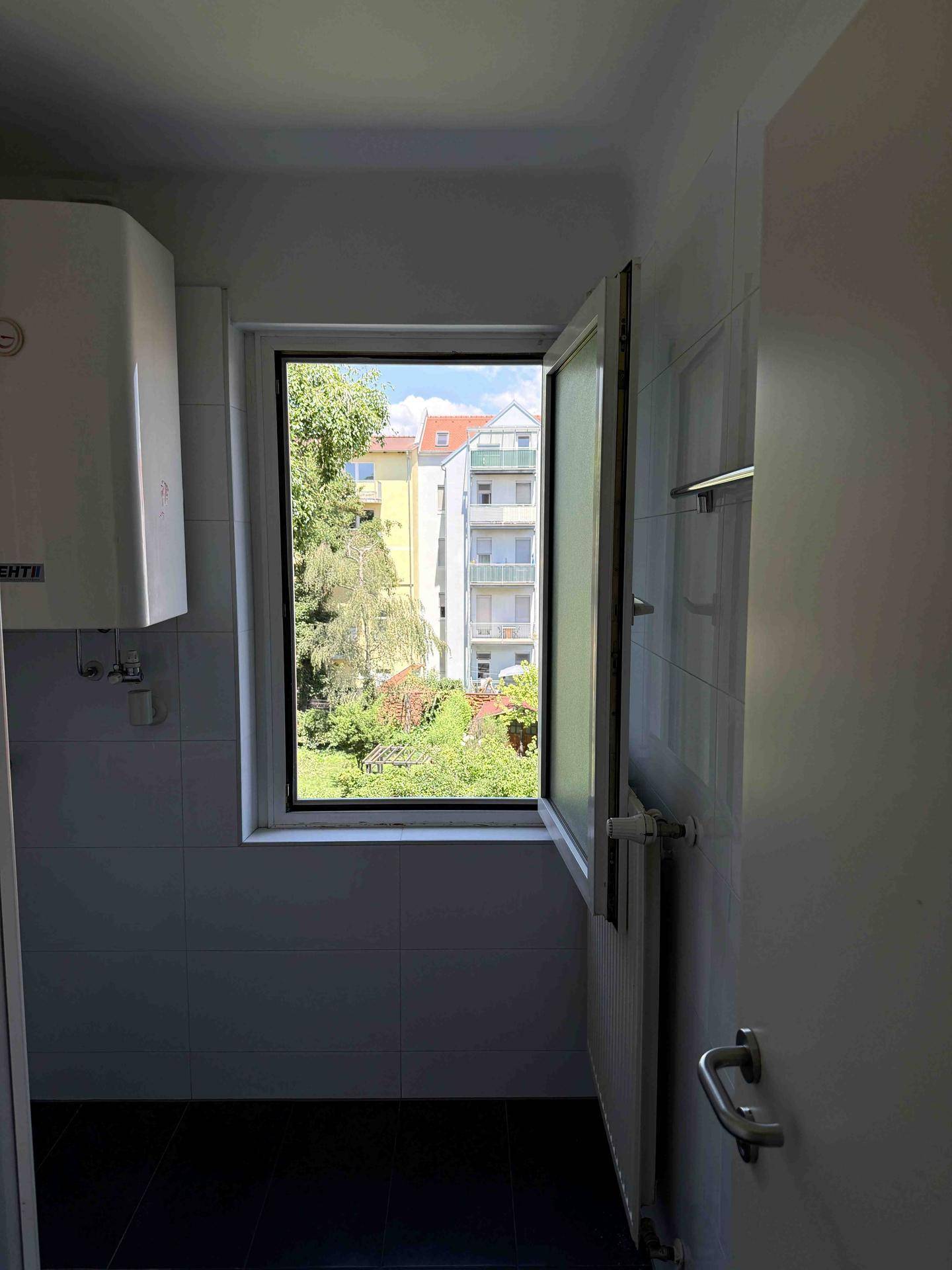 Helles Badezimmer mit Fenster, das einen grünen Ausblick bietet und für gute Belüftung sorgt.