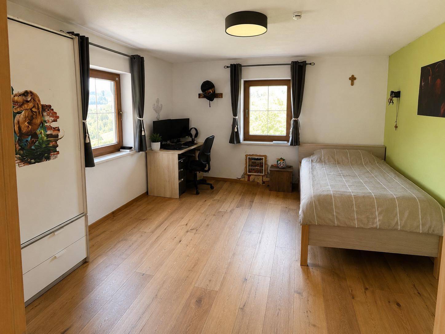 Helles Schlafzimmer mit Einzelbett, Schreibtisch und Holzboden, ideal für Kinder oder Gäste.