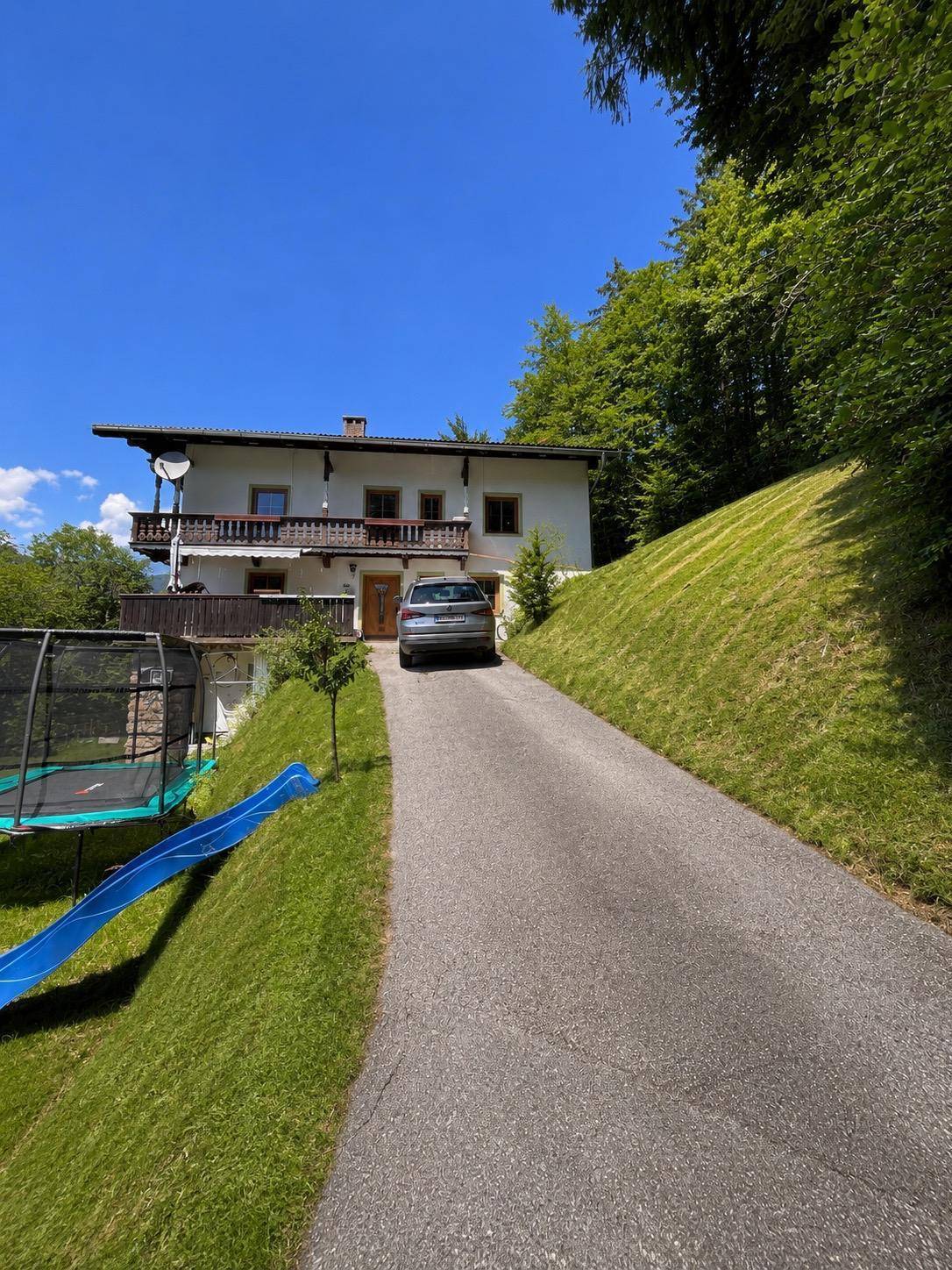 Zufahrt zum Haus mit umliegender Natur und Blick auf die Berglandschaft.