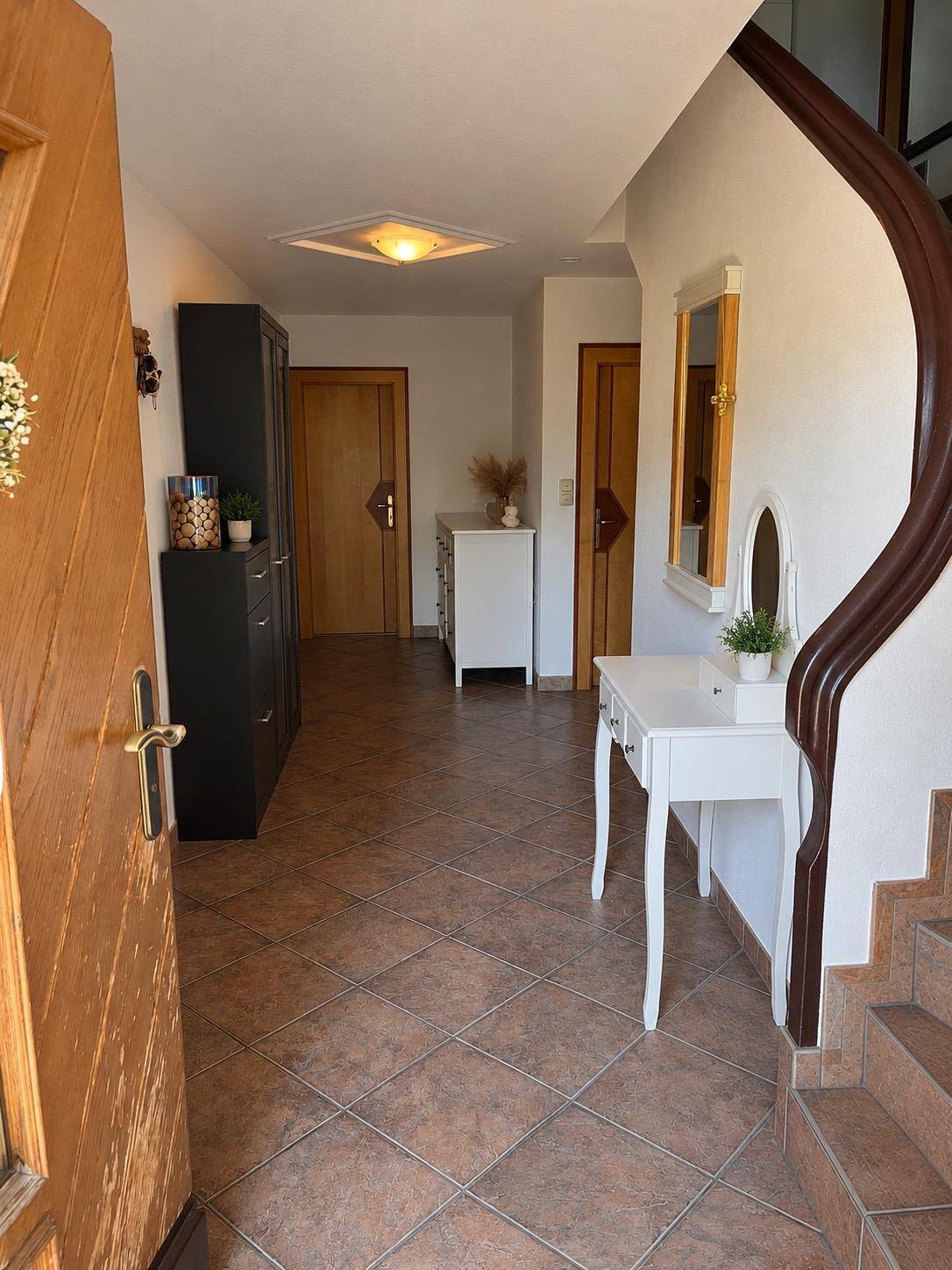 Heller Eingangsbereich mit Fliesenboden, Garderobe und Zugang zur Treppe.