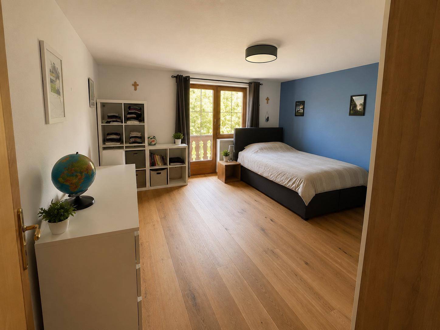 Modernes Schlafzimmer mit Doppelbett, Holzboden und Zugang zum Balkon.