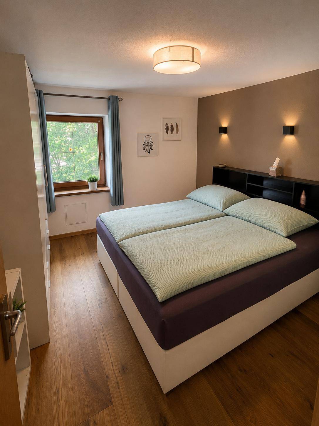 Gemütliches Schlafzimmer mit Doppelbett, Holzboden und indirekter Beleuchtung.