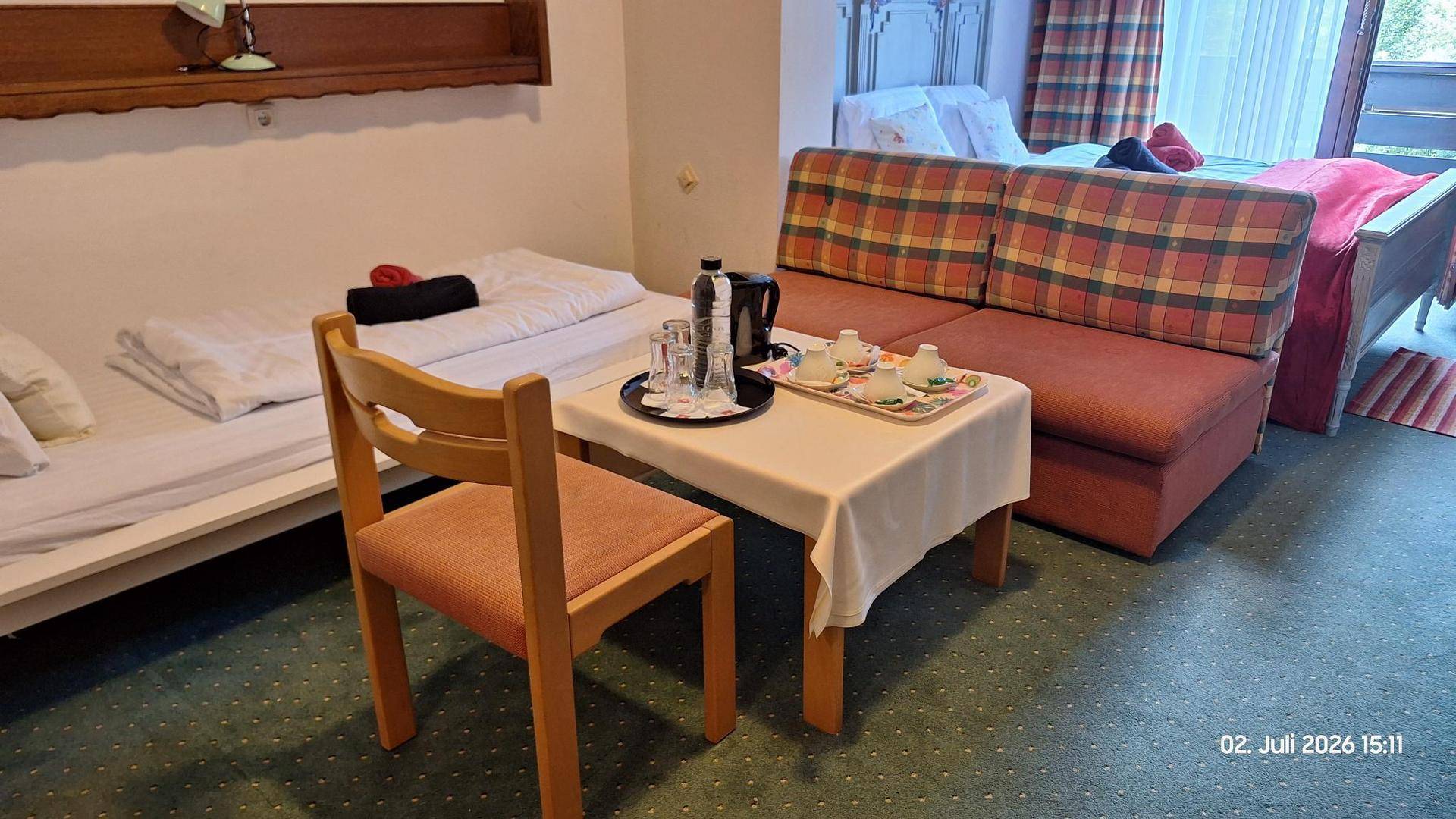 Gemütliches Schlafzimmer mit zwei Einzelbetten, einem Sofa und einem Tisch für Kaffee oder Tee.