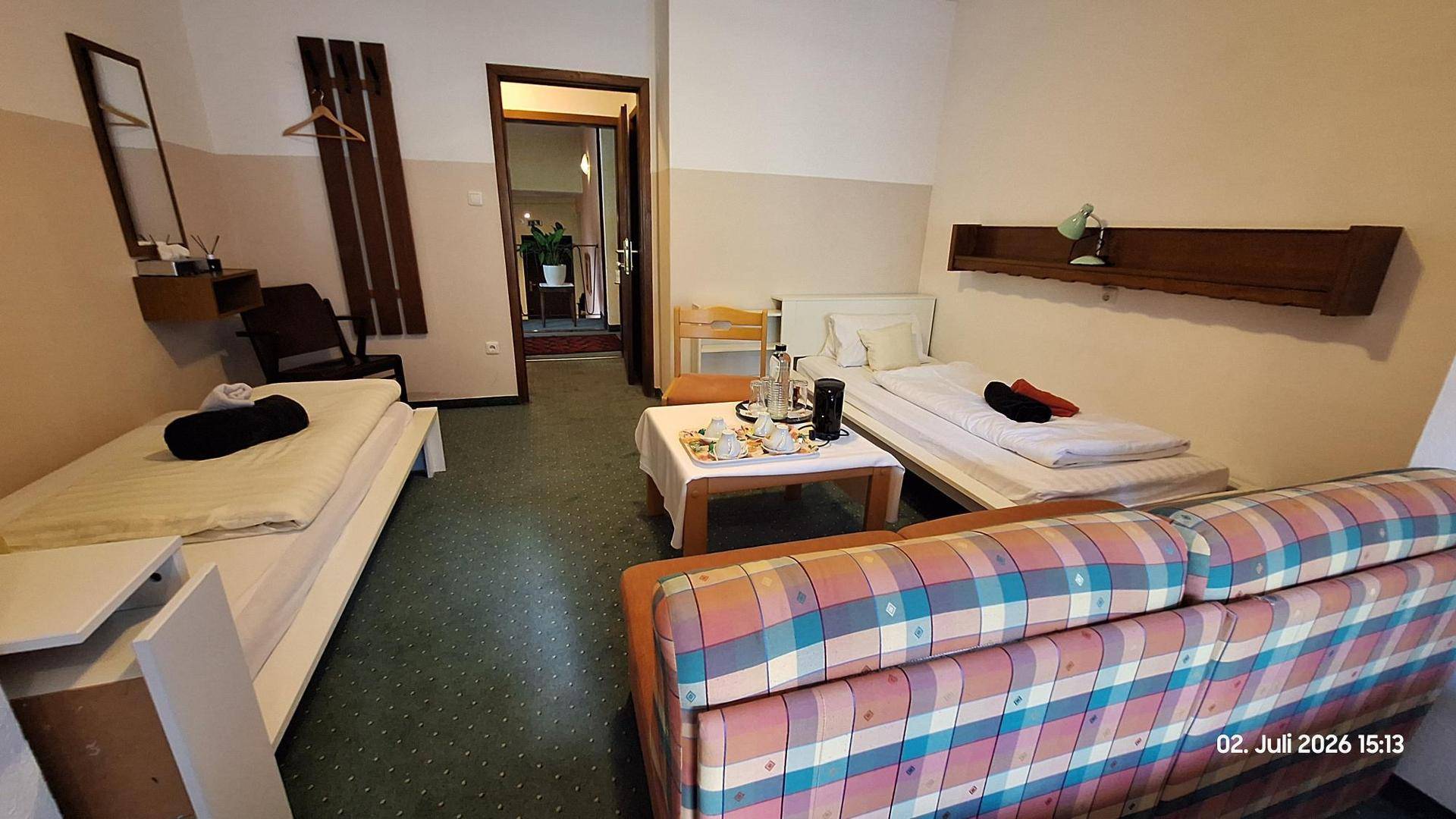 Schlafzimmer mit zwei Einzelbetten, einem Sofa und einem kleinen Tisch, in einem funktionalen Design.