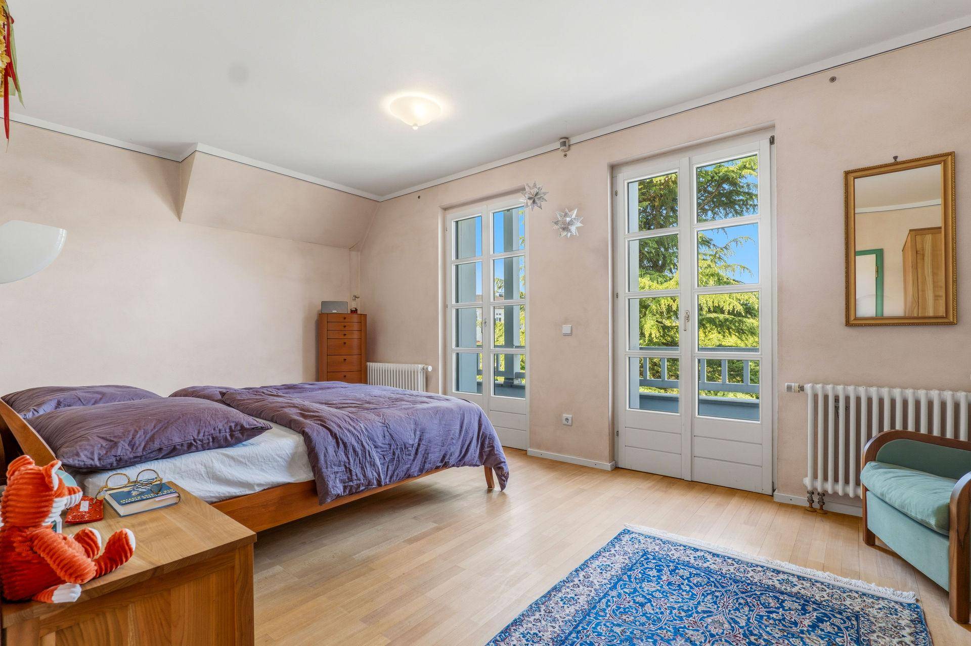 Helles Schlafzimmer mit Holzboden, zwei Einzelbetten und großen Fenstertüren zum Außenbereich.
