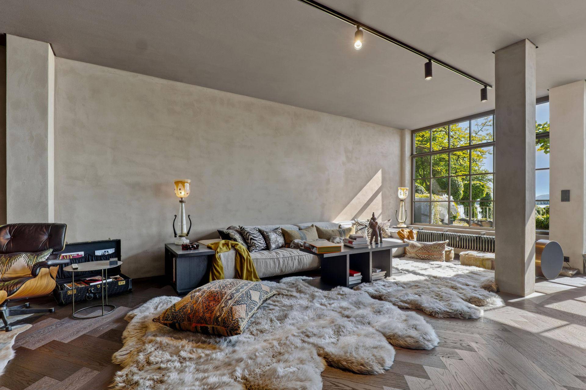 Gemütliches Wohnzimmer mit großem Sofa, flauschigen Teppichen und viel natürlichem Licht.