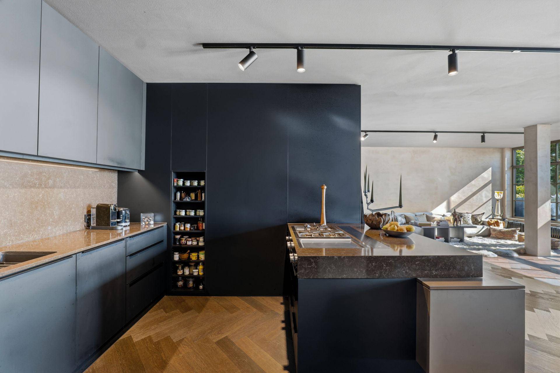 Moderne Küche mit dunkelgrauen Schränken, Kücheninsel und offenem Blick zum Wohnbereich.