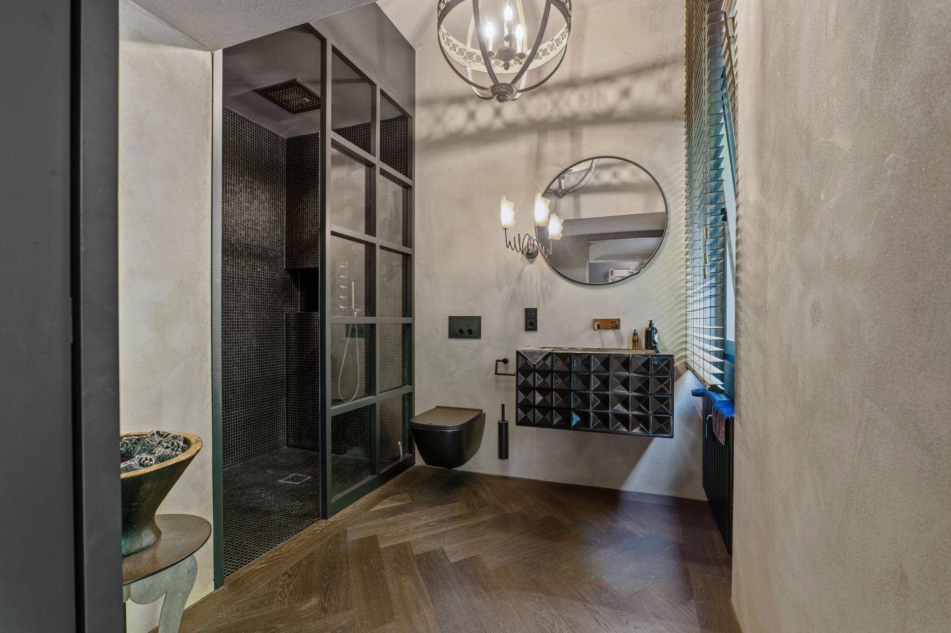 Zeitgemäßes Badezimmer mit begehbarer Dusche, rundem Spiegel und wandhängendem WC.