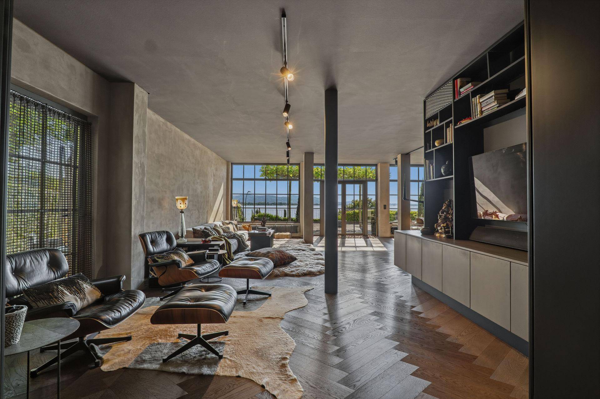 Geräumiges Wohnzimmer mit verschiedenen Sitzbereichen, Bücherregalen und weitem Seeblick.