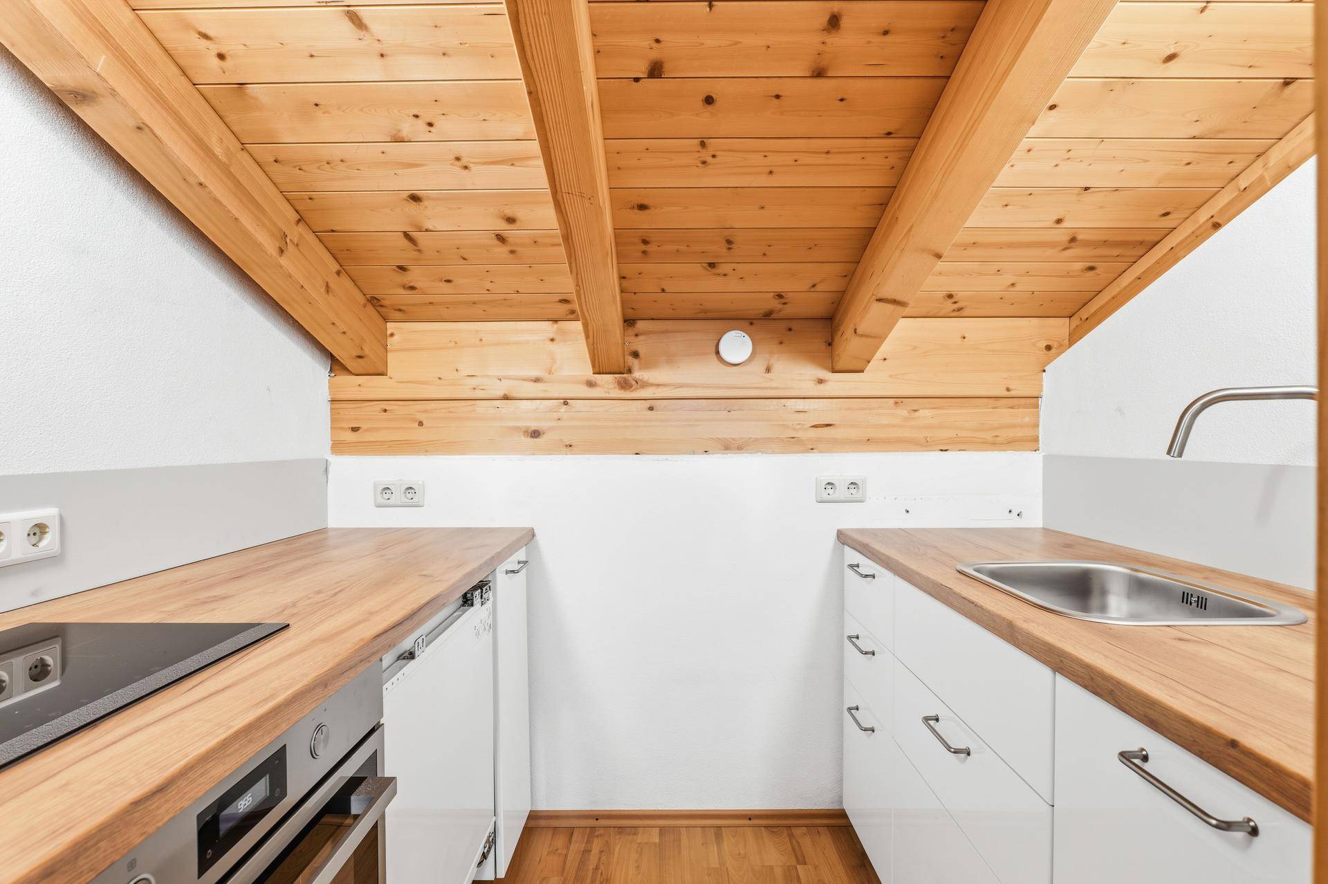 Kleine Küchenzeile im Dachgeschoss mit Holzarbeitsplatten und sichtbaren Holzbalken.