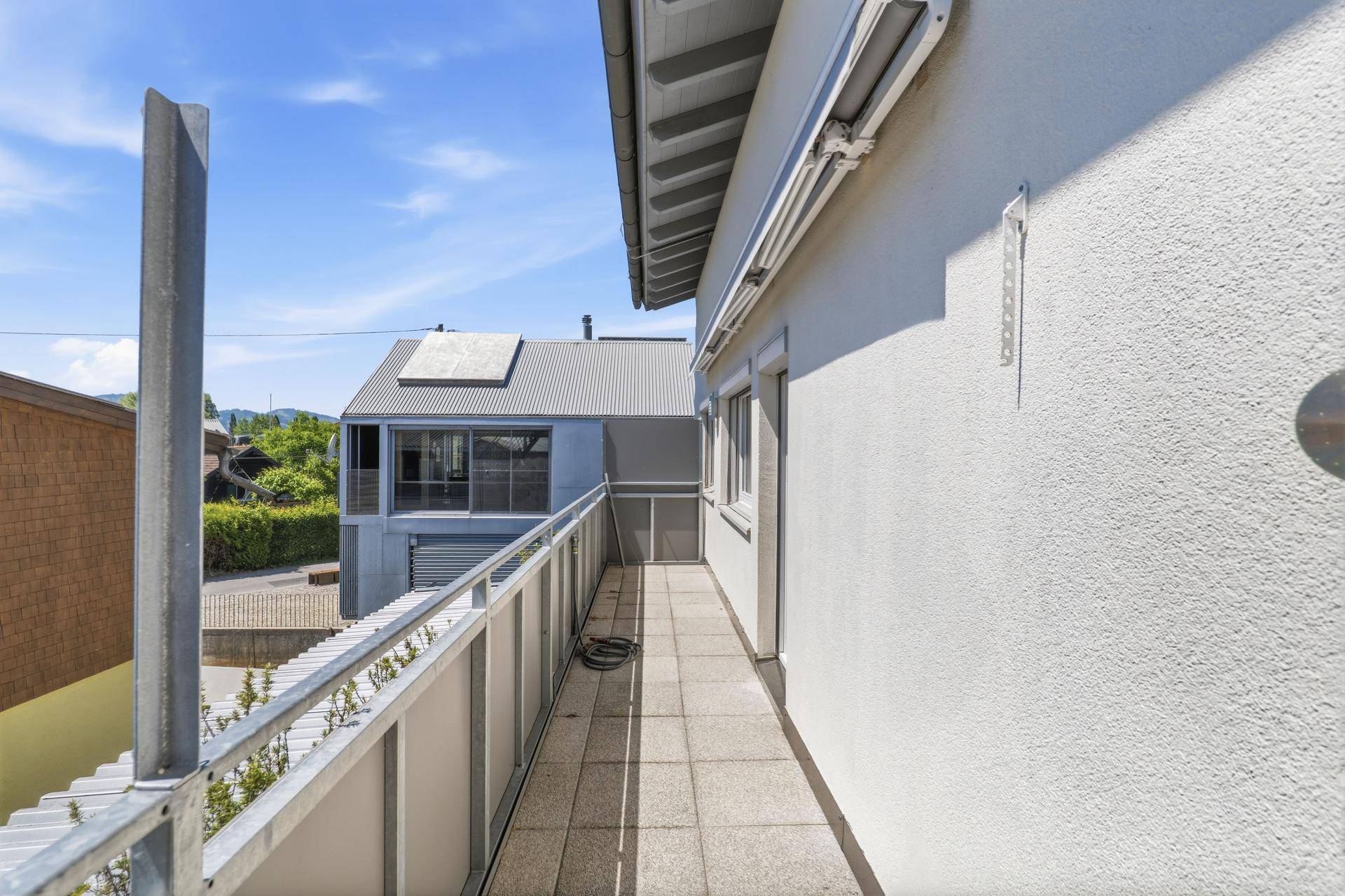 Langer, schmaler Balkon mit Fliesenboden und Metallgeländer, ideal für frische Luft.