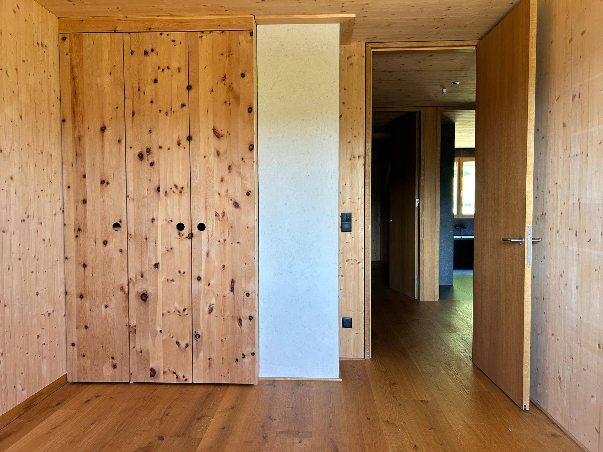 Geräumiges Zimmer mit Holzwänden, Holzboden und integrierten Holzschränken.