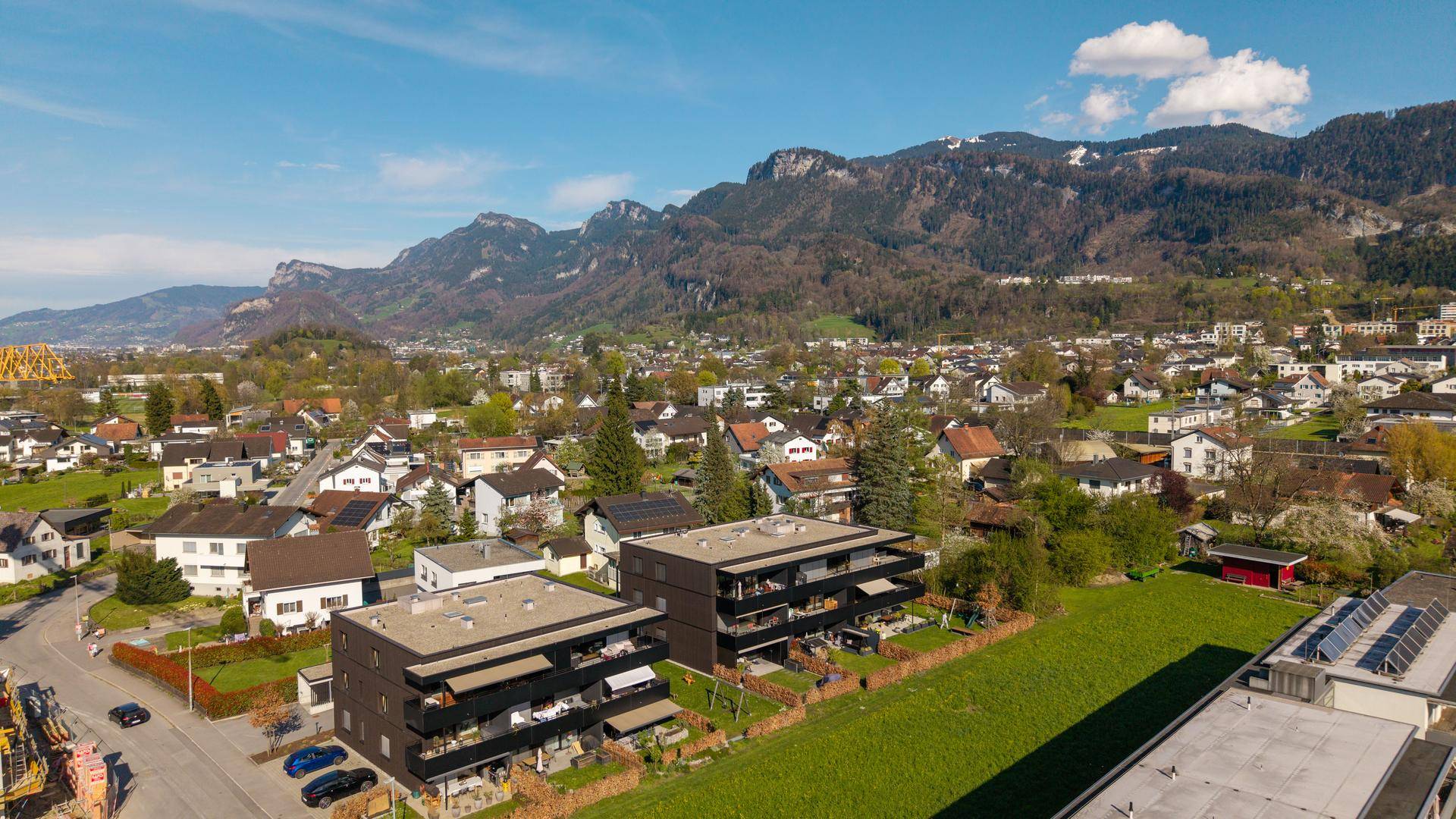 Weitläufige Luftaufnahme einer Wohnsiedlung mit Bergen im Hintergrund.