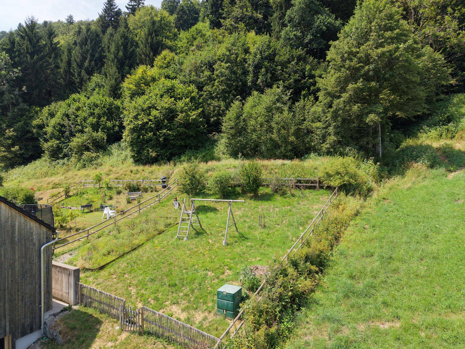 Großer Gemeinschaftsgarten mit Spielplatz und viel Grünfläche am Waldrand.