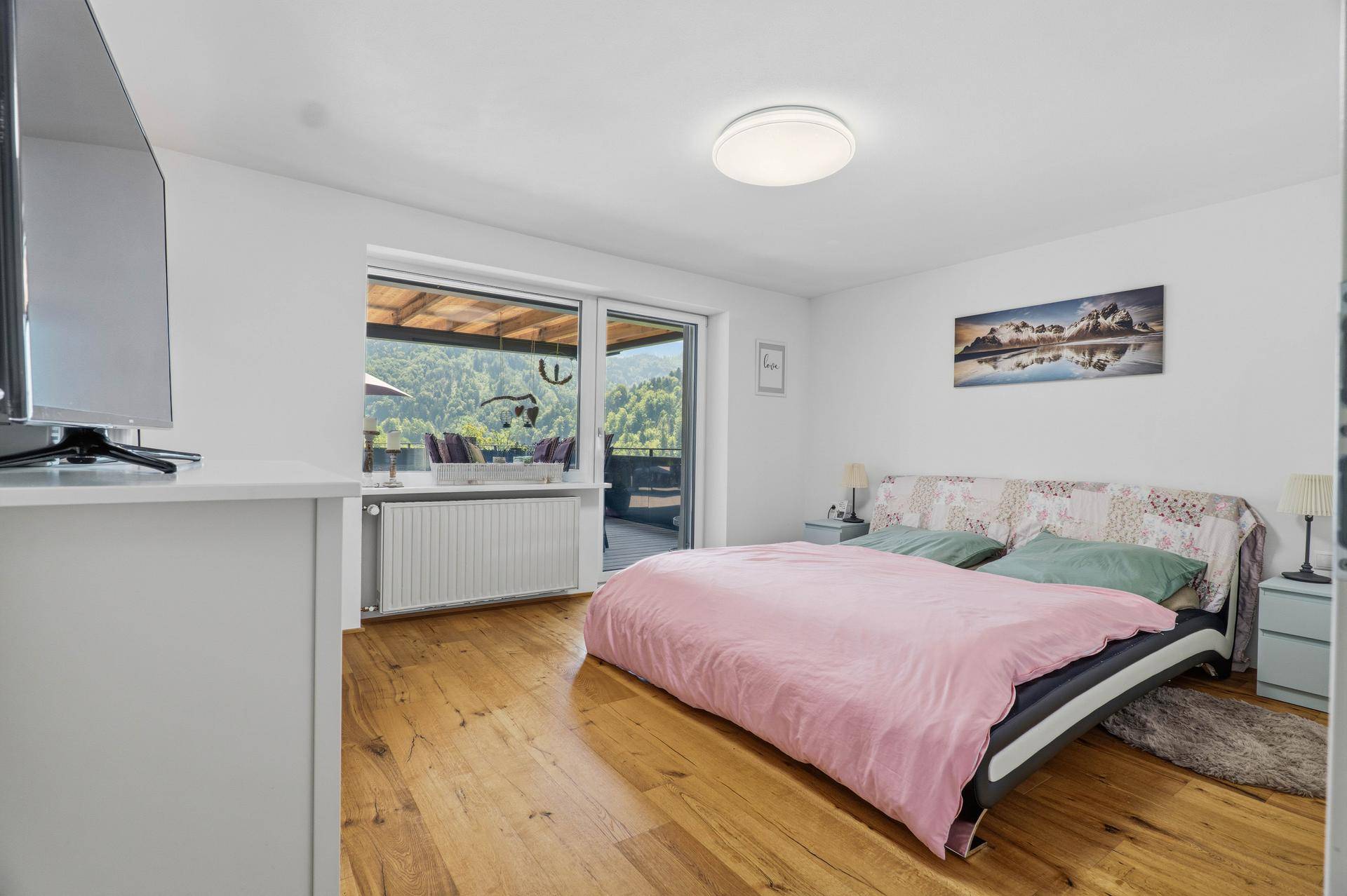 Schlafzimmer mit Holzboden, Doppelbett und Zugang zur Terrasse mit Bergblick.